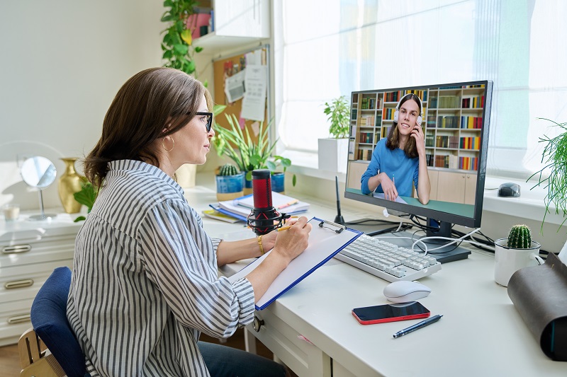 Mulher conversando com uma colega de trabalho pela internet, exemplificando como o escritório virtual pode reduzir custos na empresa.