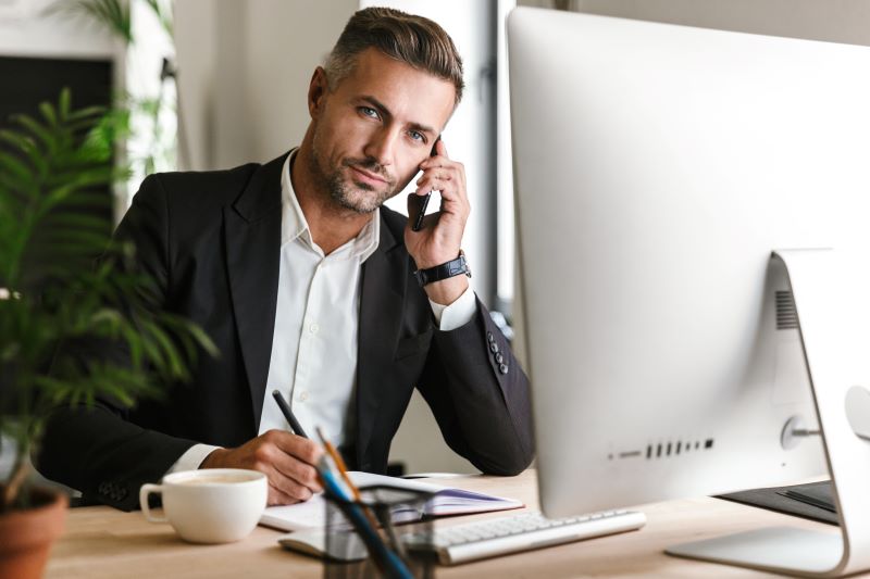 ambiente corporativo​: homem trabalhando em escritório falando ao celular