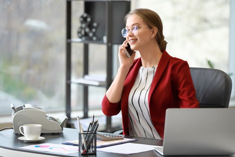 imagem profissional​: mulher sorridente no escritório falando ao celular