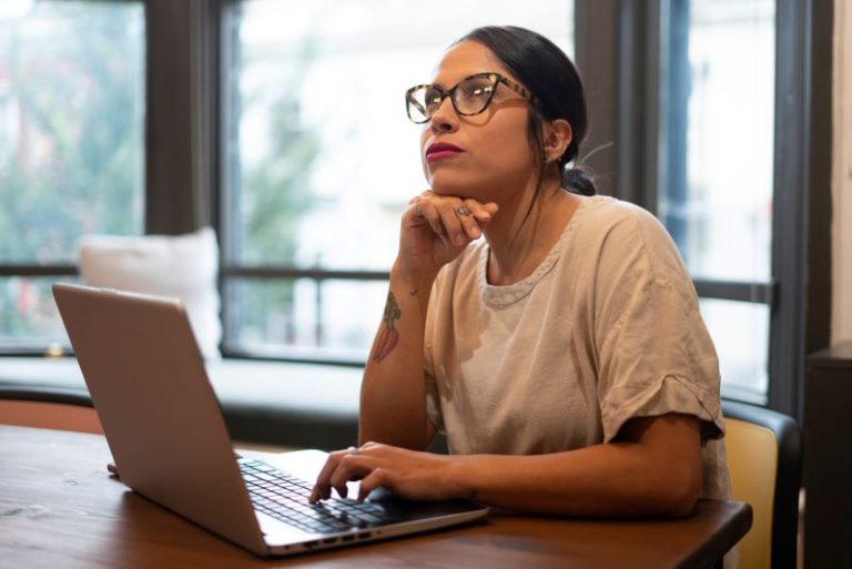 quanto custa um coworking​: mulher pensativa trabalhando em notebook